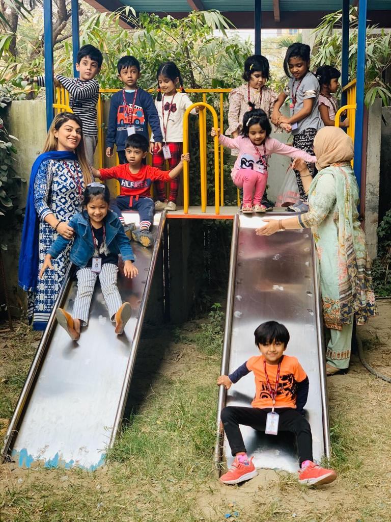 Early years children on the Playpen playground with their teachers